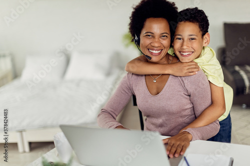 Happy African American mother and son embracing at home and looking at camera.