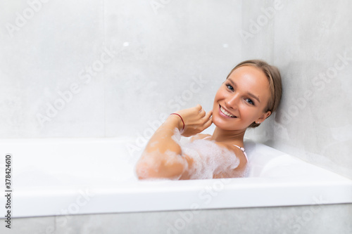 beautiful young woman taking a relaxing bath with foam
