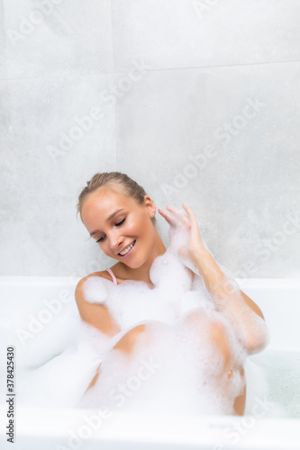 Beauty taking bath. Playful young woman lying in bathtub