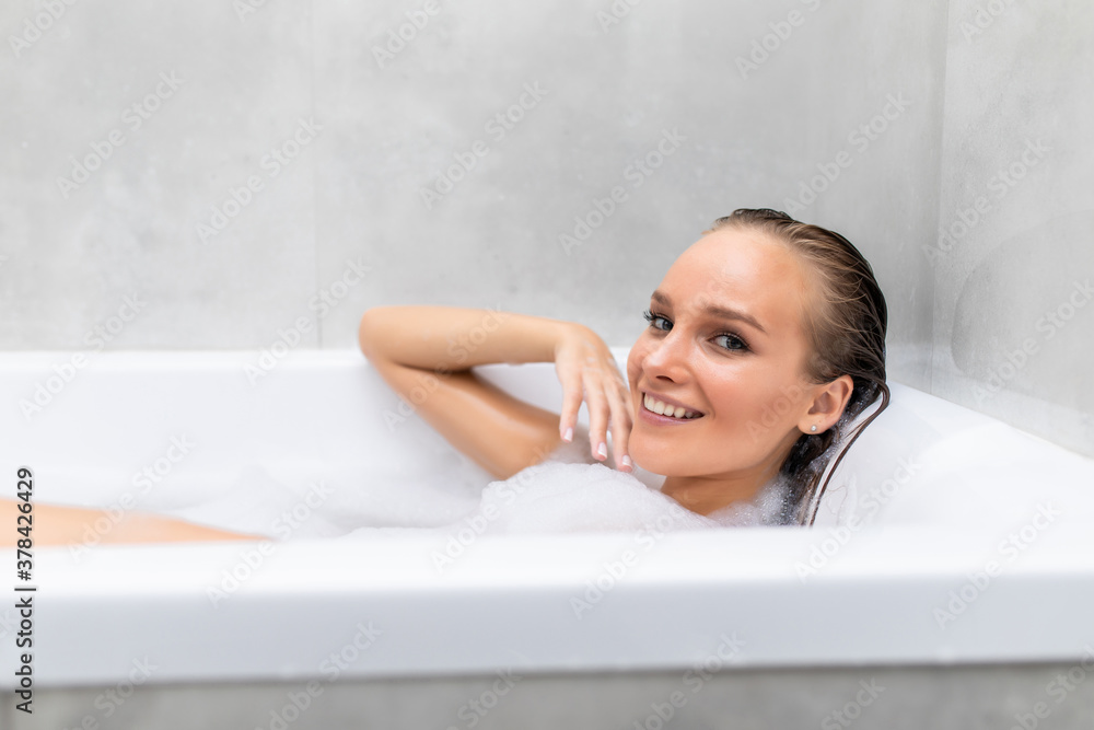 Young beautiful woman relaxing in foam in a bathtub Young beautiful woman relaxing in foam in a bathtub