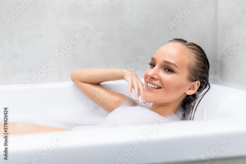 Young beautiful woman relaxing in foam in a bathtub