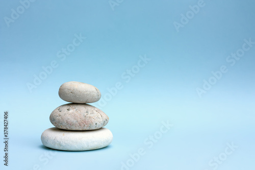 Tree grey roundstones on light blue pastel color background. Spa stones  zen like concept.