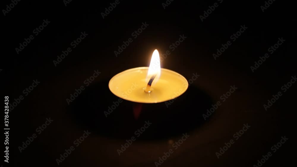 One burning candle. A Christmas candle burns in the dark. close-up. One burning candle. A Christmas candle burns in the dark. close-up.