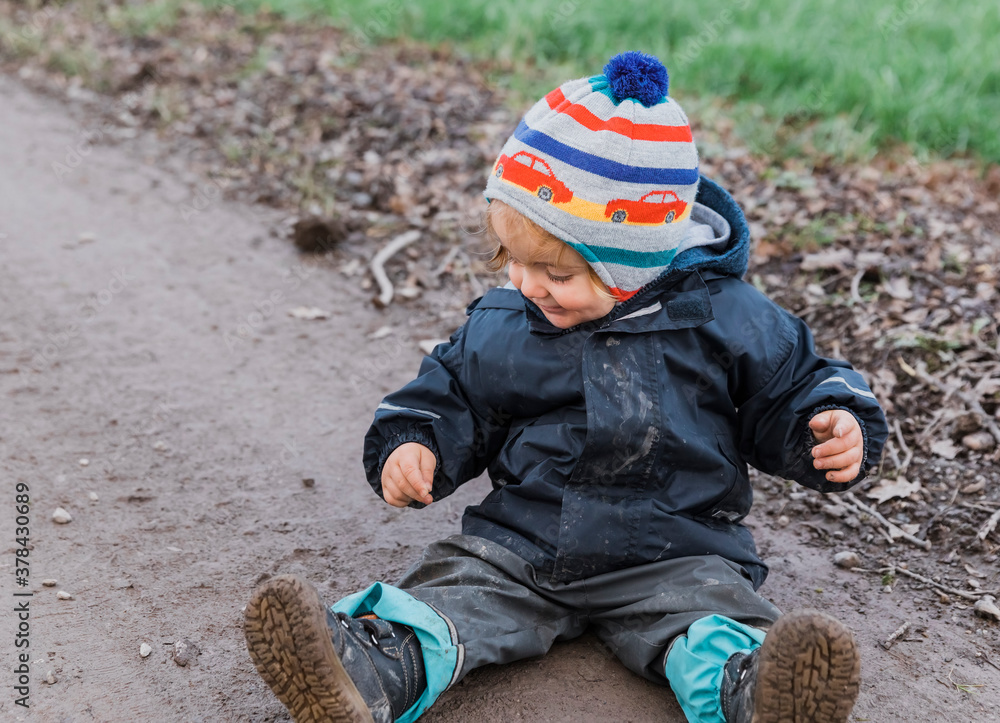 Happy toddler girl sitting with muddy pants on dirt road Happy toddler girl sitting with muddy pants on dirt road
