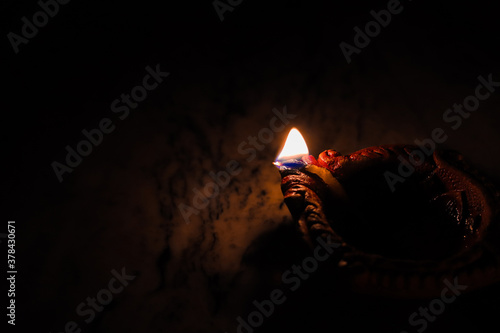 Fototapeta Naklejka Na Ścianę i Meble -  earthen oil lamp lit on the occasion of deepavali, a hindu festival of light with selective focus on lamp and background and foreground blur