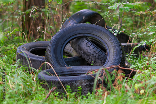 used car tires discarded in the wood - nature pollution with consumer waste photo