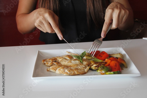 Photography chica come pollo con vegetales, alimentos en el restaurant, coccion perfecta