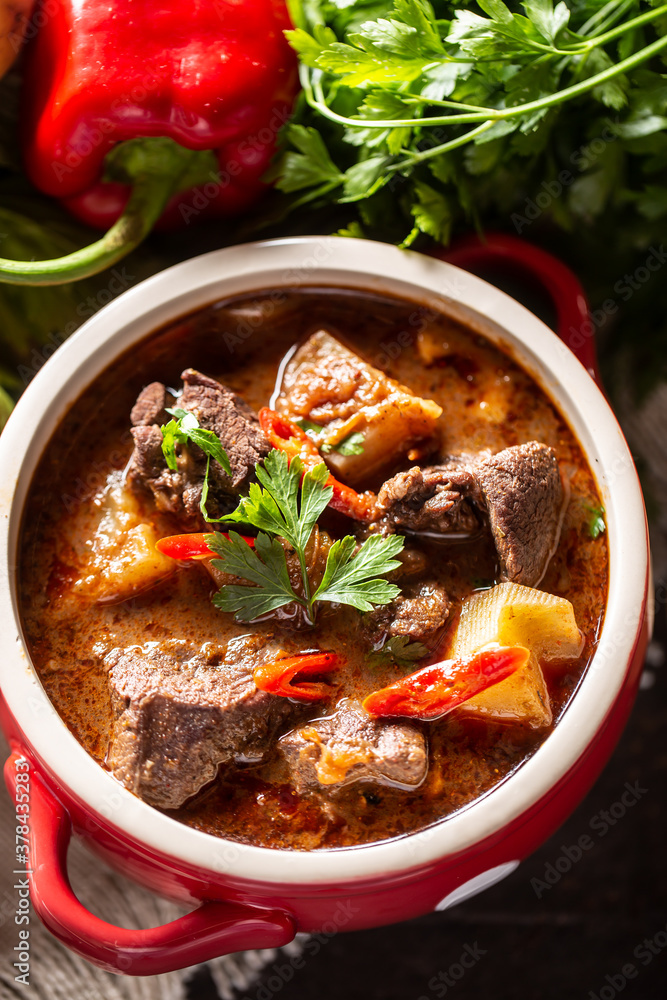 Bowl of goulash soup with meat, potatoes, chillies and parsley Bowl of goulash soup with meat, potatoes, chillies and parsley