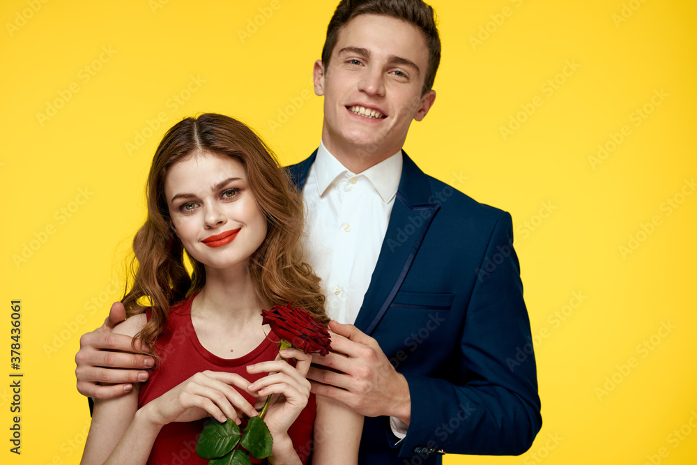 lovers man and woman with a red rose in their hands hugging on a yellow background romance relationship love family lovers man and woman with a red rose in their hands hugging on a yellow background romance relationship love family