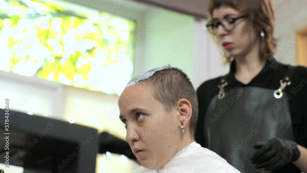 Hairdresser applies bleach to a woman's hair. The salon is at home. Hairdresser applies bleach to a woman's hair. The salon is at home.