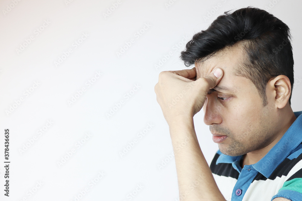 a young indian male with hands on forehead with a very worried expression isolated on white with copy space for text. a young indian male with hands on forehead with a very worried expression isolated on white with copy space for text.