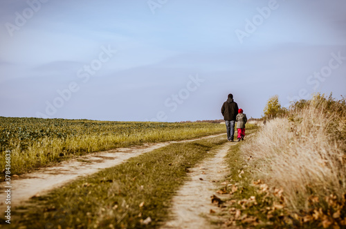 man with child walking together in dramatic sad dark atmosphere leaving the place back view