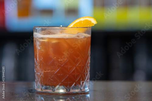 Closeup shot of a glass of iced cocktail with orange on a bar cunter photo