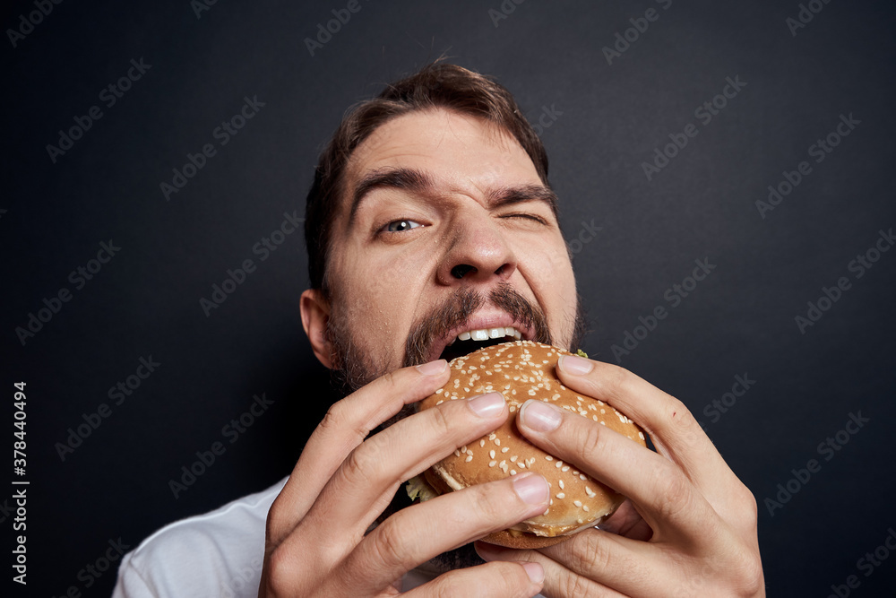 Man eating hamburger fast food restaurant Gourmet eating dark background Man eating hamburger fast food restaurant Gourmet eating dark background