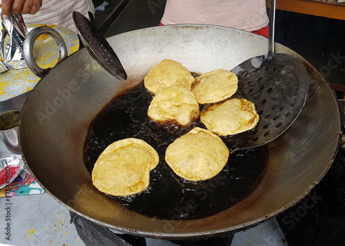 fried food kachauri puri pile deep fried in oil in a big steel frying pan photo