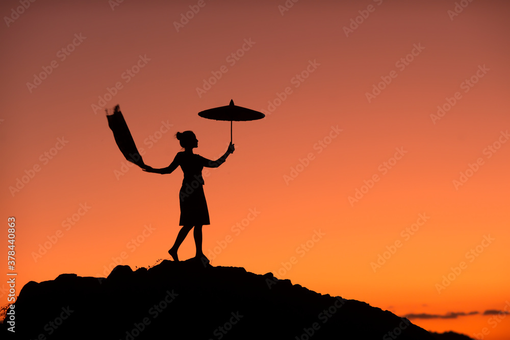  silhouette picture of a beautiful woman standing in an umbrella on a rock In the middle of the Mekong River