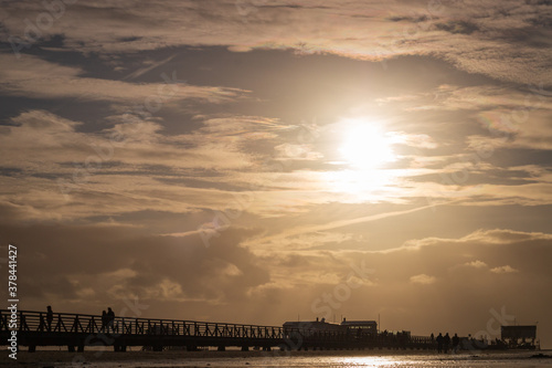 People on wooden seabridge at north sea beach in Sankt Peter-Ording, Germany.