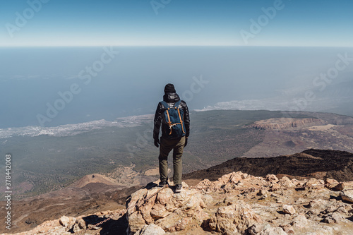 Hiker with backpack standing on top of a mountain..Success, freedom and happiness, achievement in mountains peak. Active sport concept. Guy stands on a cliff and admires view. Man hiking.