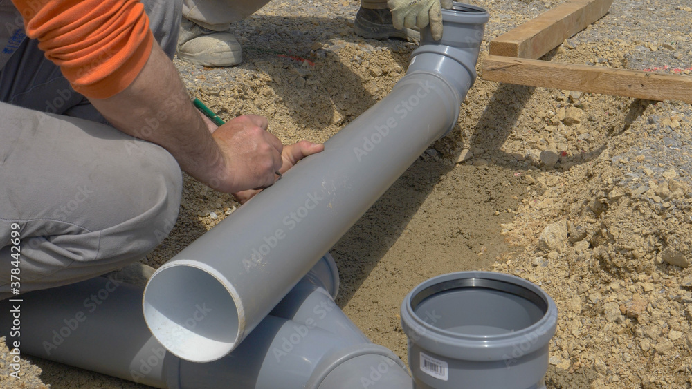 CLOSE UP: Unrecognizable builder marks a plastic sewage pipe with a pencil. CLOSE UP: Unrecognizable builder marks a plastic sewage pipe with a pencil.