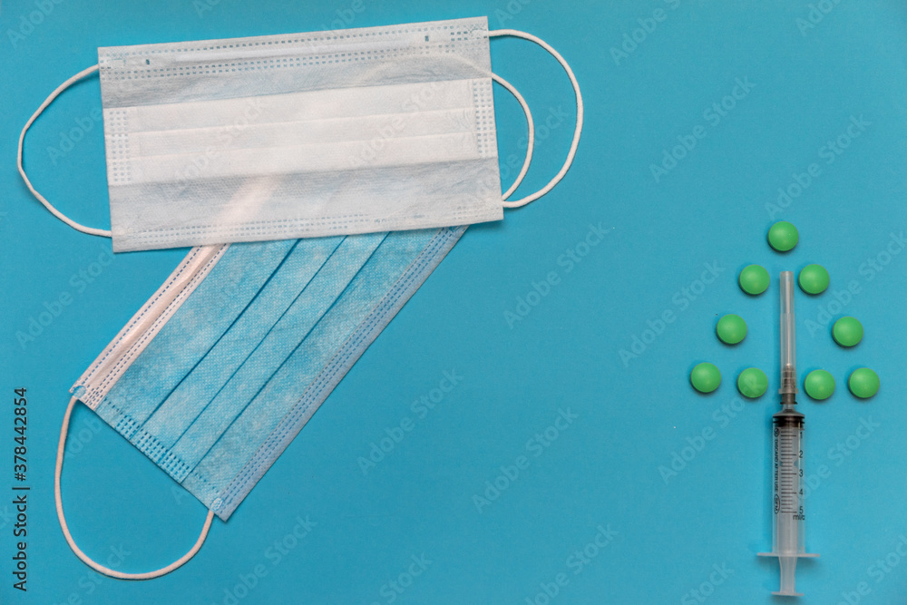 Blue white masks, syringe, pills on a blue background. Medicine new year 2021. High quality photo Blue white masks, syringe, pills on a blue background. Medicine new year 2021. High quality photo