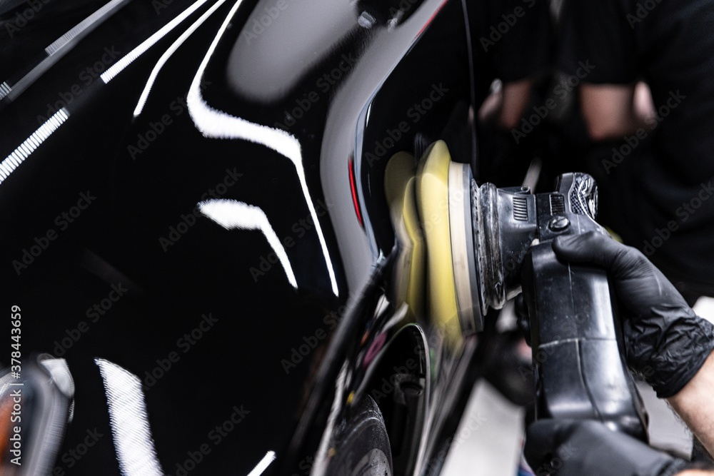Car detailing studio worker polishing car varnish