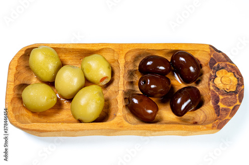 Black and green olives in a small wooden bowl on a white surface background