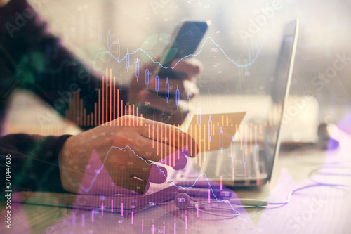 Double exposure of man s hands holding and using a phone and financial graph drawing. Analysis concept.