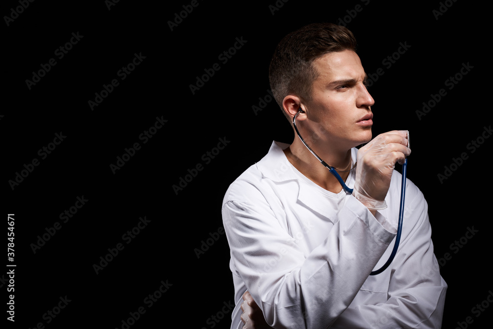 professional doctor in a medical gown with a stethoscope around his neck against a dark background cropped view professional doctor in a medical gown with a stethoscope around his neck against a dark background cropped view