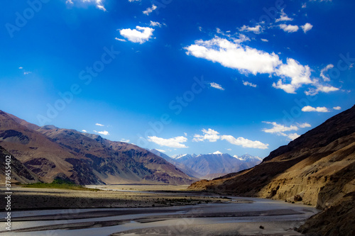 shades of cloud in High dynamic range image of barren mountain in a desert with river and deep blue sky in ladakh, Jammu and Kashmir, India
