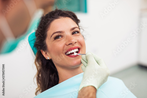 Beautiful woman sitting on dental chair and having dental treatment.