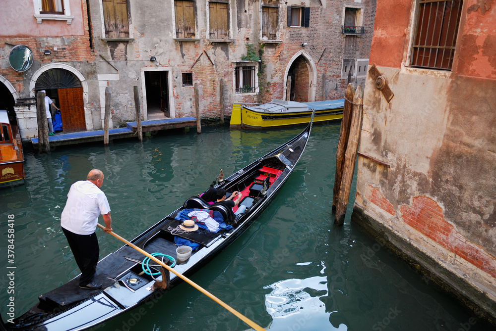Gondolier maneuvering his boat around a canal corner in Venice