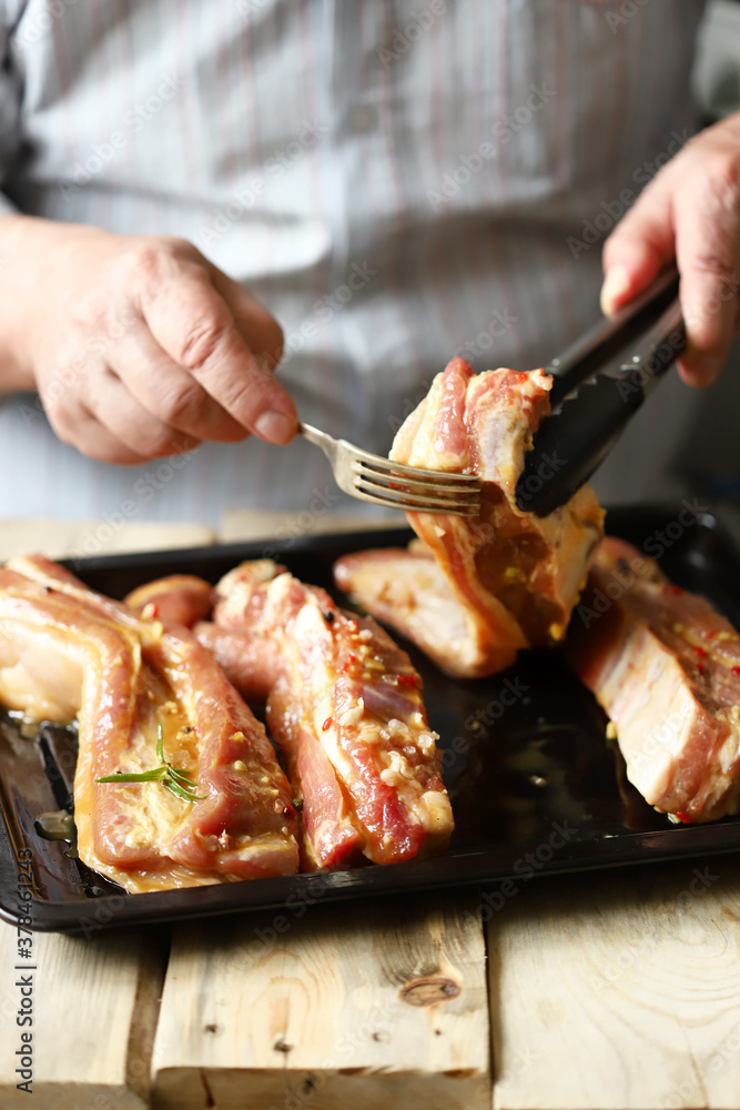 Marinated pork ribs on a pan. The chef marinates pork ribs. Barbecuing ribs.