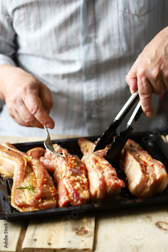 Marinated pork ribs on a pan. The chef marinates pork ribs. Barbecuing ribs.