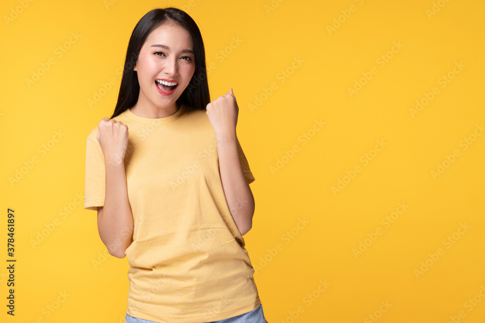 Joyful young woman successful with excitement up, keeps hands raised arm while standing over isolated yellow background. Joyful young woman successful with excitement up, keeps hands raised arm while standing over isolated yellow background.