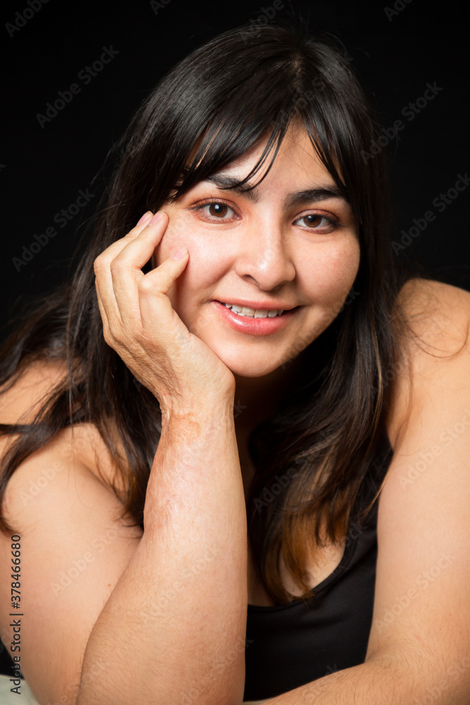 Portrait Hispanic woman smiling looking at camera on black background - inclusive beauty- curvy woman - body positive character, feminism, self love, beauty concept Portrait Hispanic woman smiling looking at camera on black background - inclusive beauty- curvy woman - body positive character, feminism, self love, beauty concept