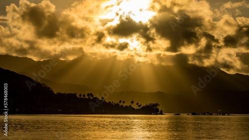 Piercing Sun Rays trough the clouds above the island of Raiatea, French Polynesia. photo