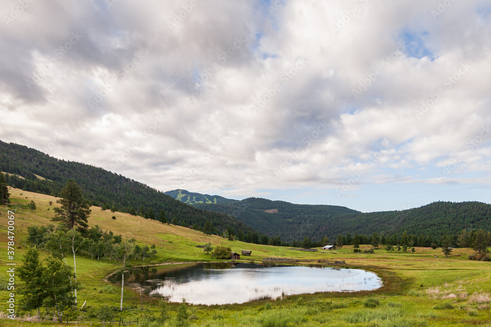 Large pond in swampy meadow among rolling hills country side british columbia Canada