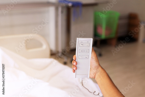 Patient hands using remote for adjustment level sick bed at hospital