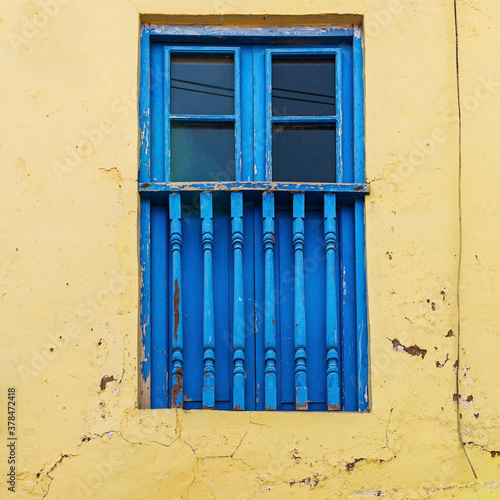 Colonial style blue balcony window and yellow facade, Cusco, Peru.