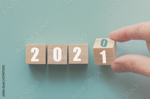 Hand flipping over wooden block of 2020 to 2021, New Year Resolutions, business concept