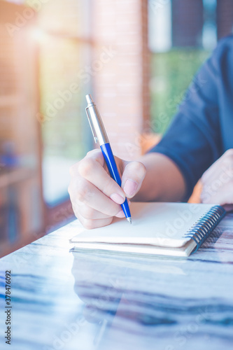 Woman is writing on a notebook with a pen in the office.