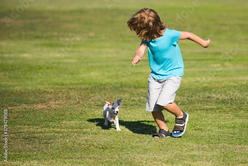 Happy child boy run with a dog outdoor.