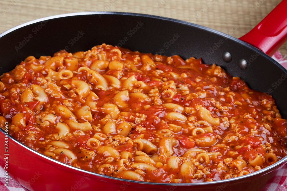 Goulash and noddles cooking in a red skillet Goulash and noddles cooking in a red skillet