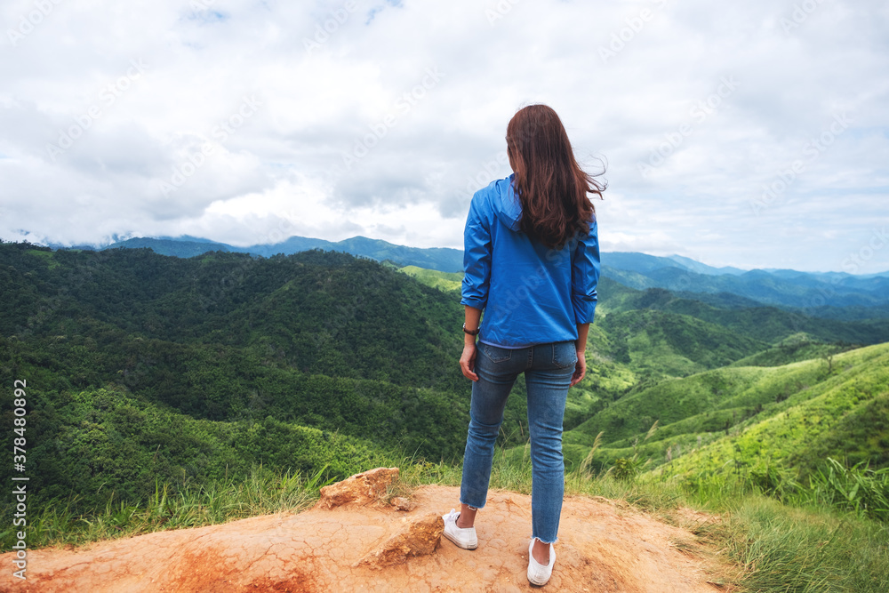 Rear view image of female traveler looking at a beautiful green mountains view