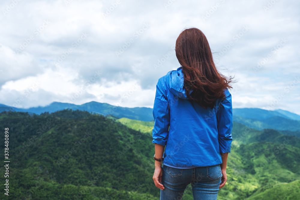 Rear view image of female traveler looking at a beautiful green mountains view Rear view image of female traveler looking at a beautiful green mountains view