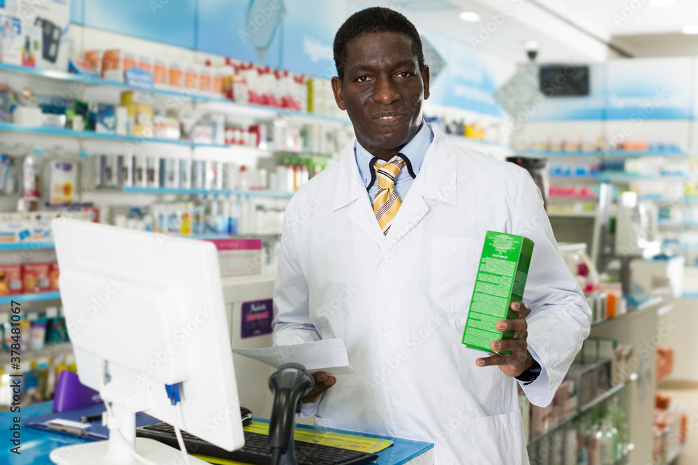 Confident African American man pharmacist offering medicines in drugstore.