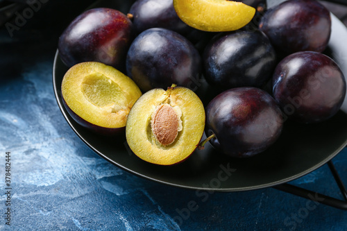 Plate with ripe plums on color background, closeup photo