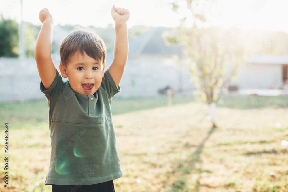 Happy caucasian boy playing outside and gesturing the win sign smiling in the garden in a summer day Happy caucasian boy playing outside and gesturing the win sign smiling in the garden in a summer day
