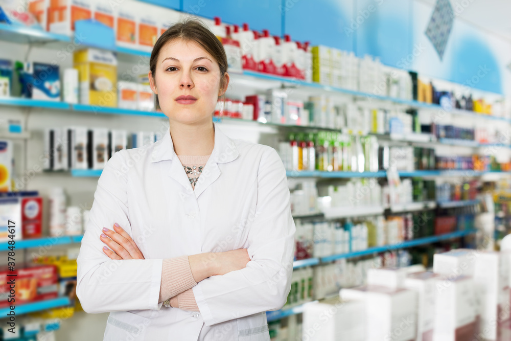 Portrait of young positive female pharmacist in modern pharmacy