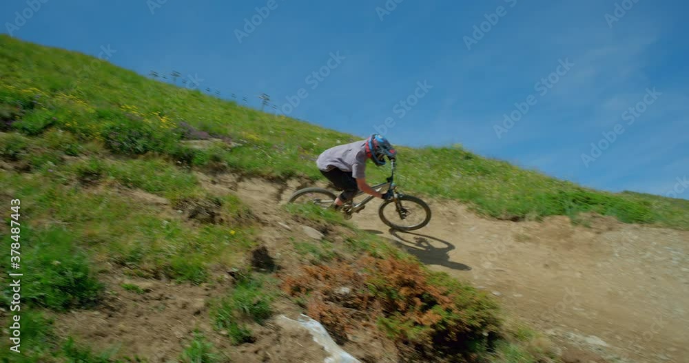 A mountain biker riding around a berm (steep banked turn) on a downhill mountain bike course in Tignes, French Alps. A mountain biker riding around a berm (steep banked turn) on a downhill mountain bike course in Tignes, French Alps.
